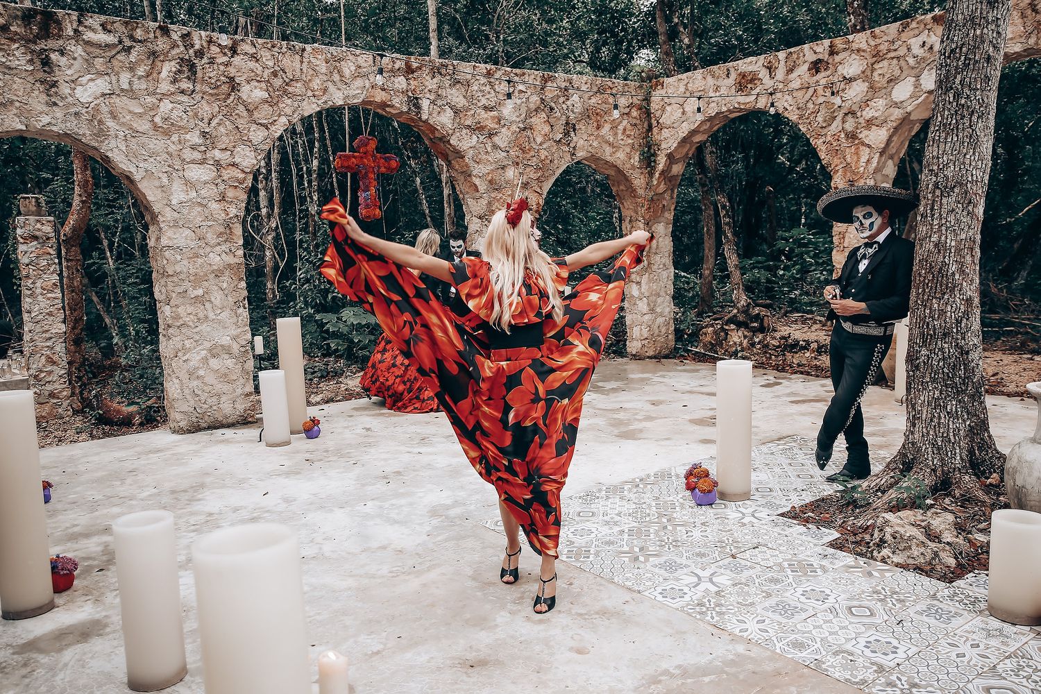 Gothic wedding ceremony setup with white candles and stone archway in outdoor woodland setting.