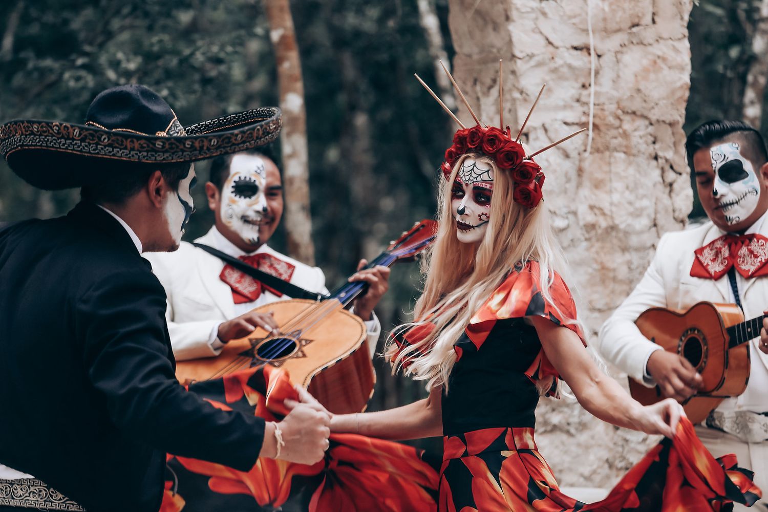 Couple in Mexican folk costumes dancing and celebrating during a Day of the Dead themed shoot.