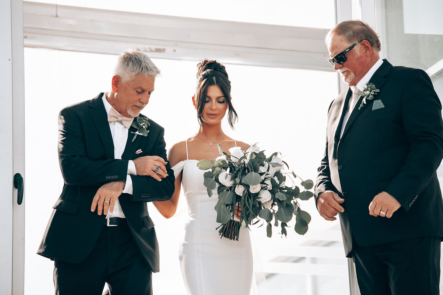 Wedding party members sharing emotional moments in bright indoor venue.