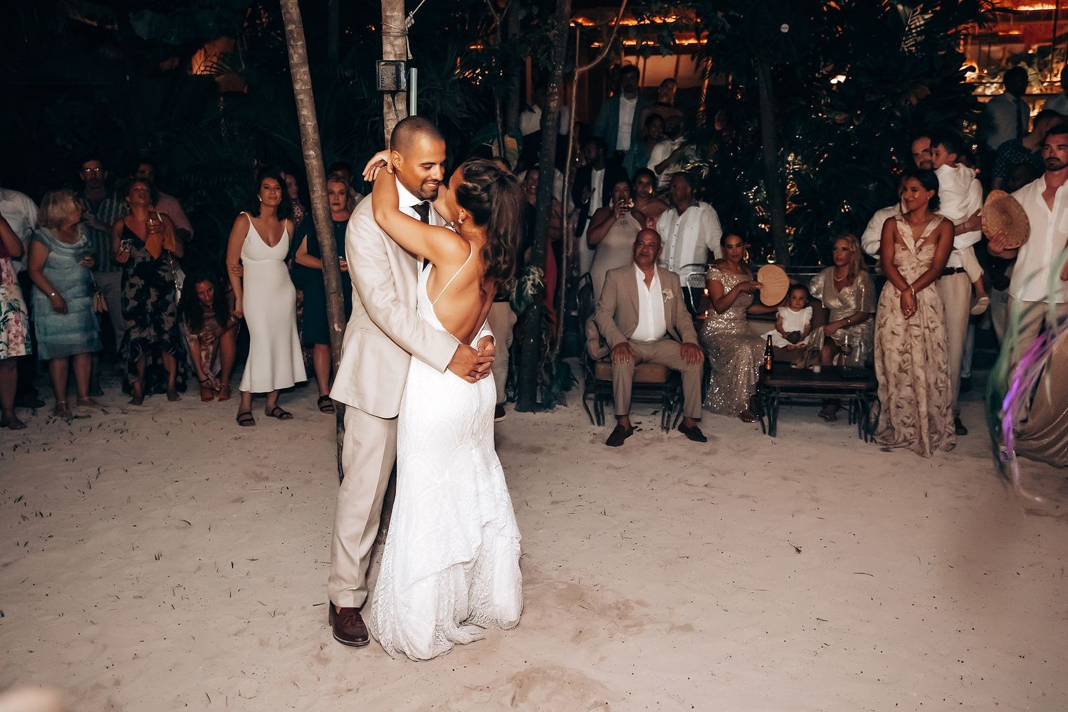 Wedding reception dance party on the beach at night with guests celebrating.