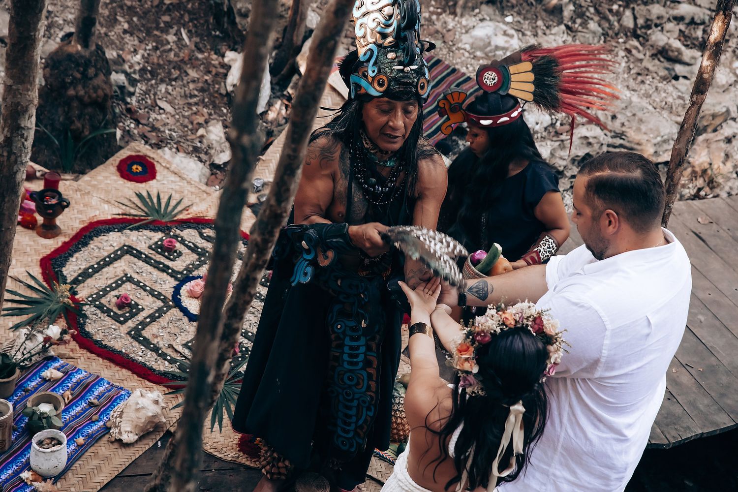 Sacred ceremony participants gathered around traditional Mayan ritual objects and textiles.