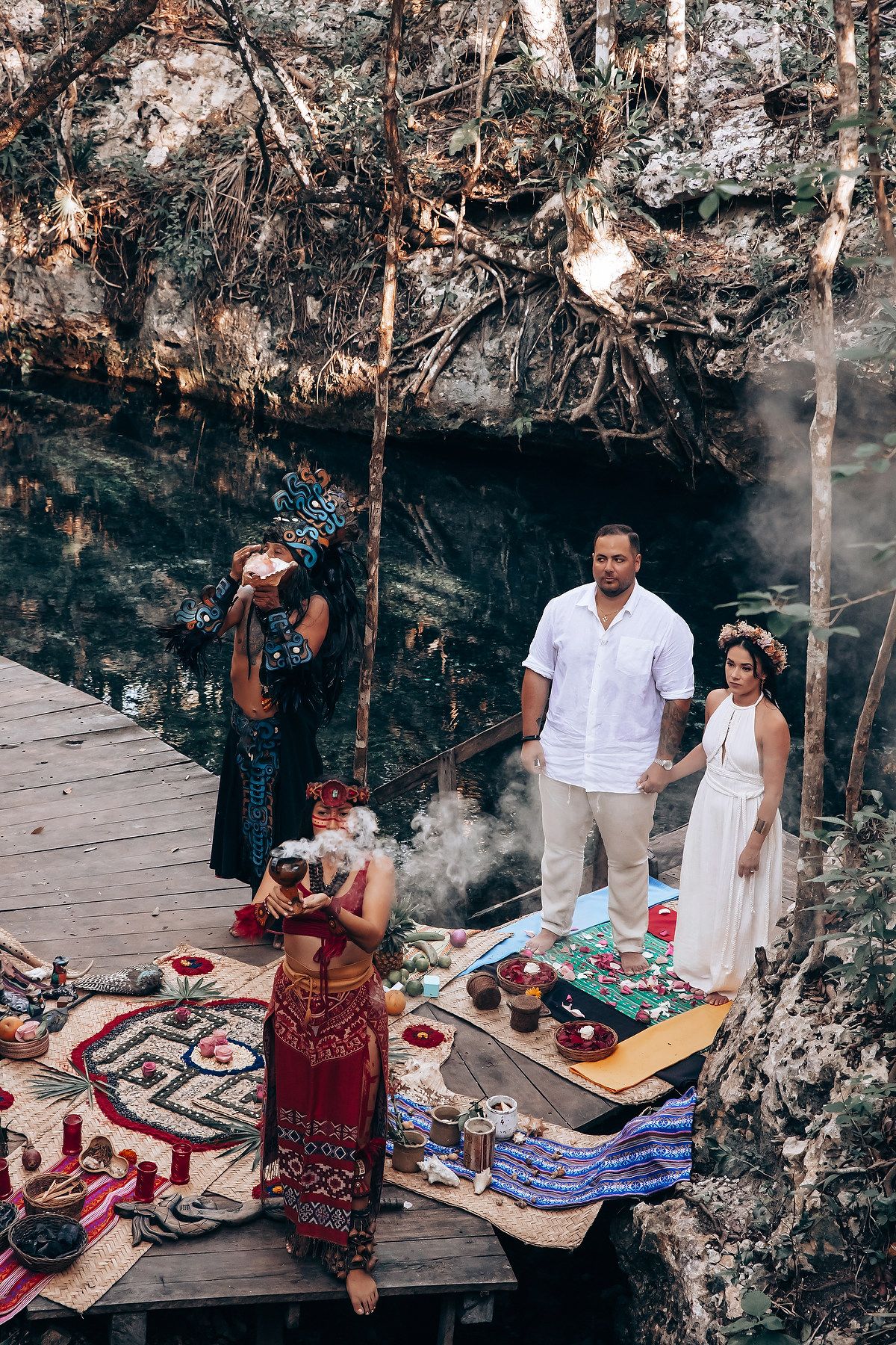 Traditional ceremony taking place on wooden platform with colorful textiles and ceremonial items.