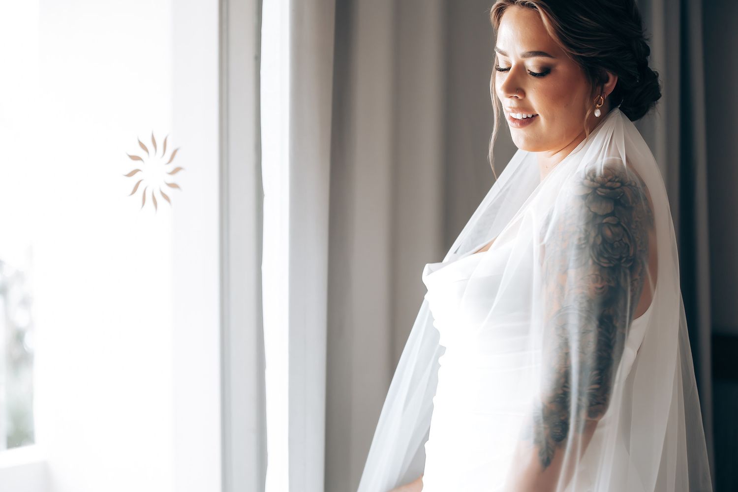 Wedding dress detail with delicate veil in soft natural window light.