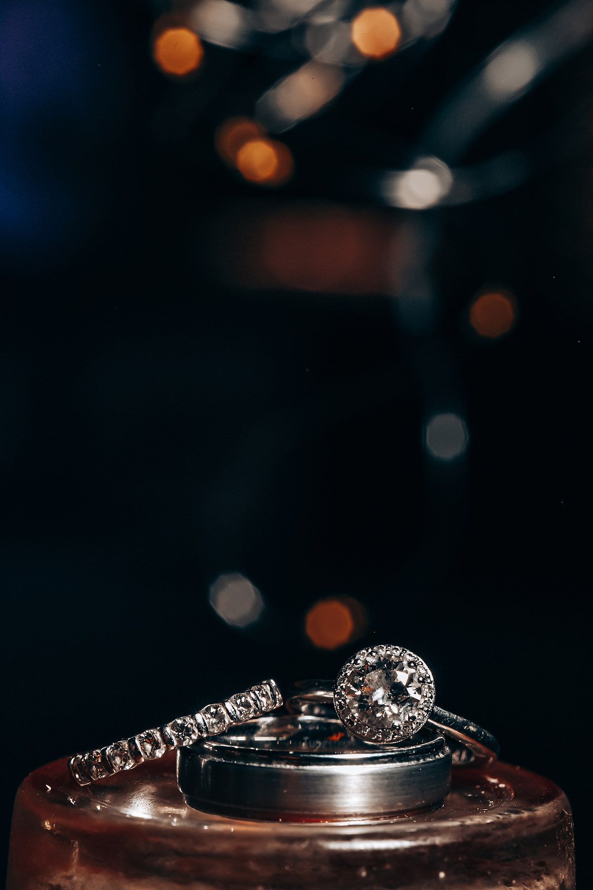 Wedding rings displayed with bokeh lighting effects in dark setting.