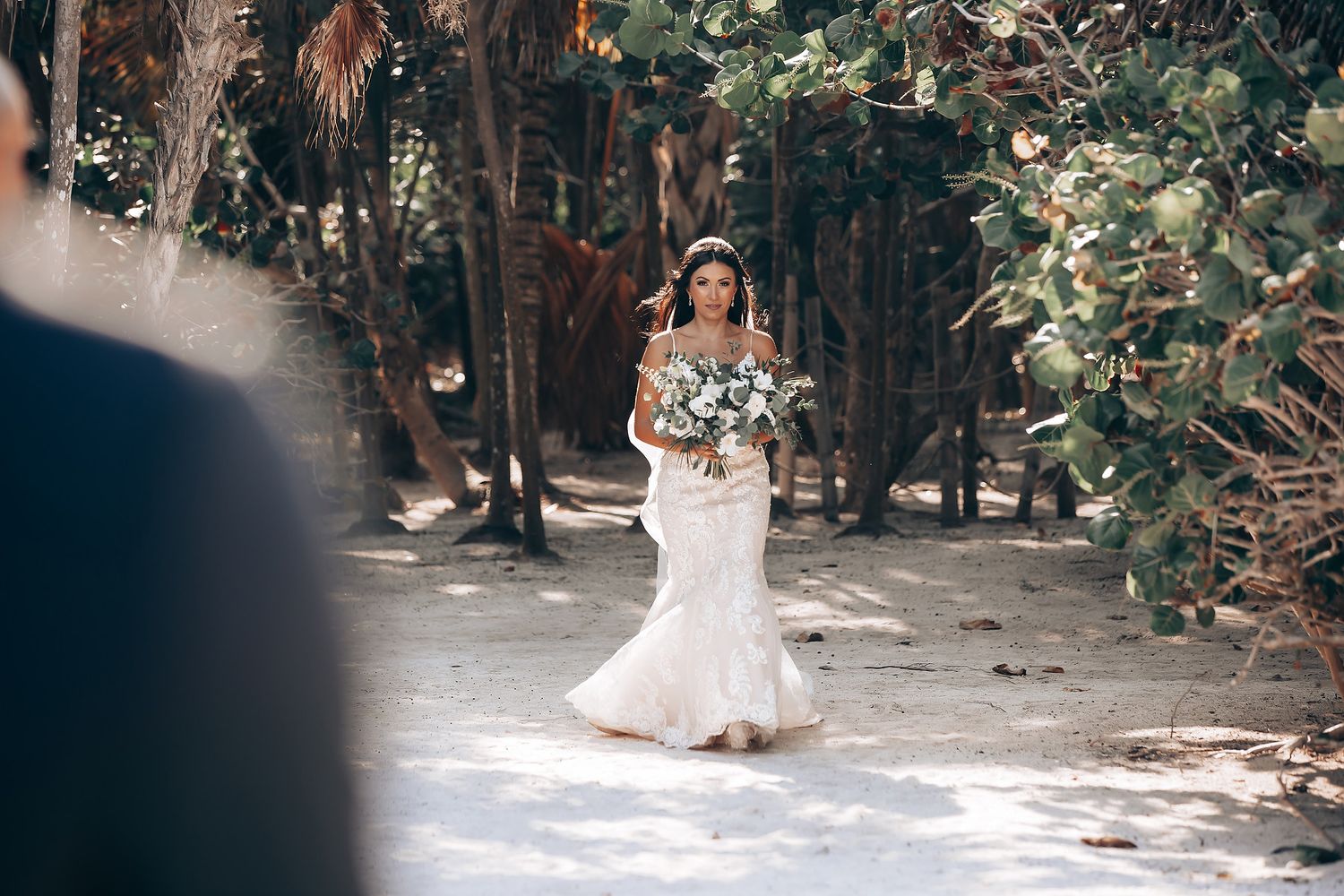 Outdoor wedding ceremony setup with wooden chairs arranged in rows under tropical palm trees.