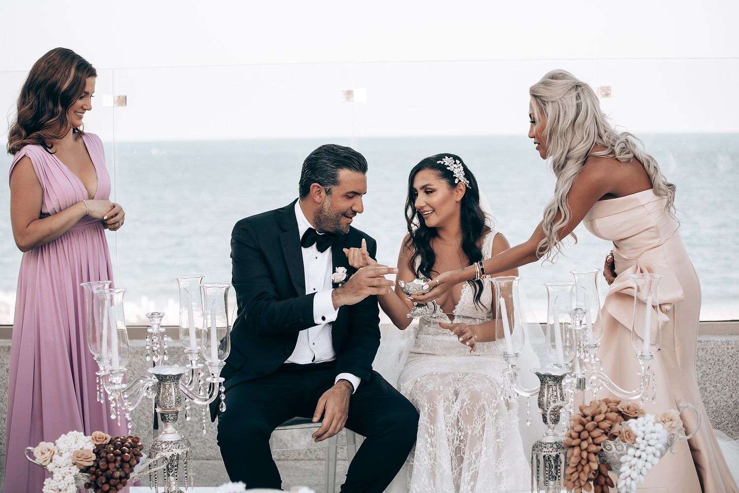 Wedding celebration on a beach with soft pink and white decor elements.