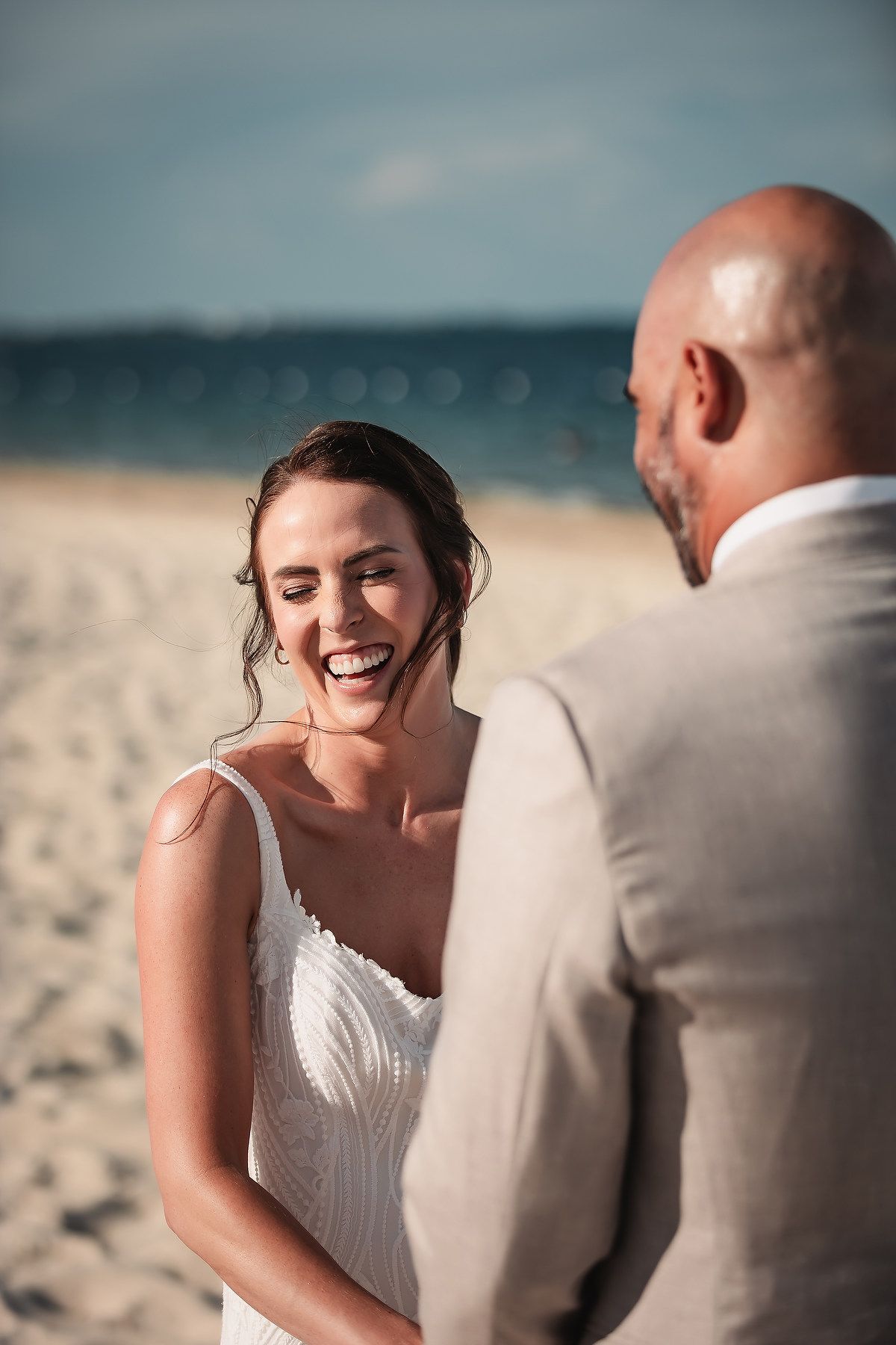 A couple shares joyful moments during their beach wedding photoshoot.