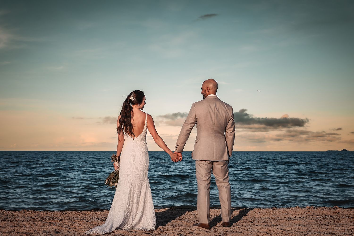Romantic beach scene at sunset with couple walking along the shoreline.