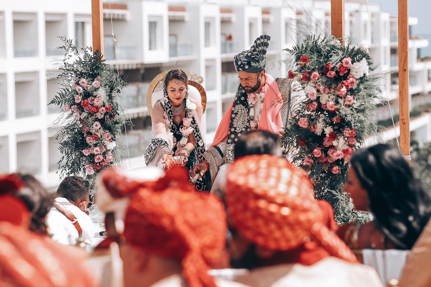 Decorated wedding mandap with floral arrangements and greenery under a white canopy.