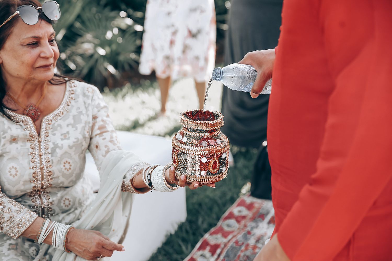 A traditional wedding ceremony with people wearing red and white attire and holding decorative items during a cultural celebration.