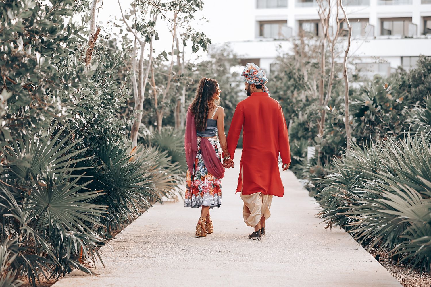 A romantic outdoor photoshoot featuring vibrant red and floral outfits against a garden backdrop.