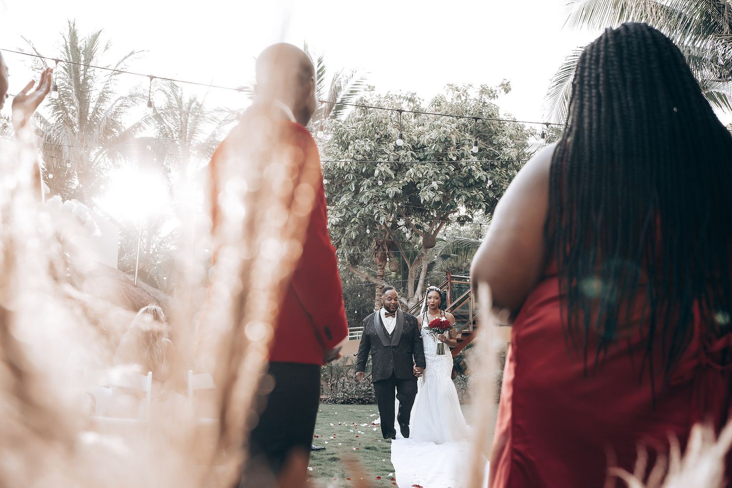 Soft focus wedding party scene with blurred figures in red dresses and formal attire.