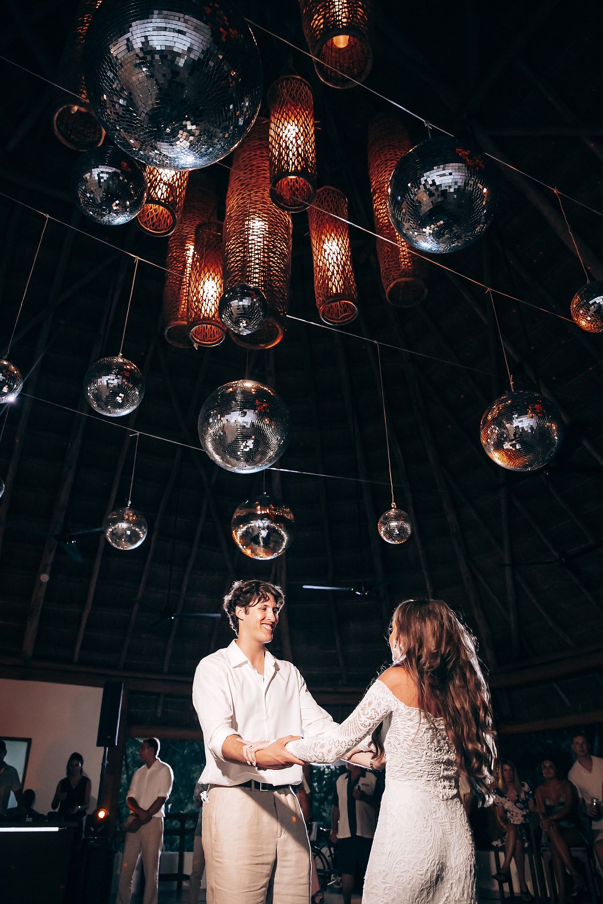 Wedding reception dance floor under disco balls and copper lantern lighting.