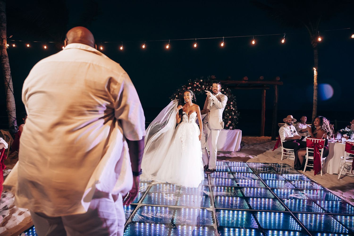 Evening wedding reception with string lights and glowing dance floor.