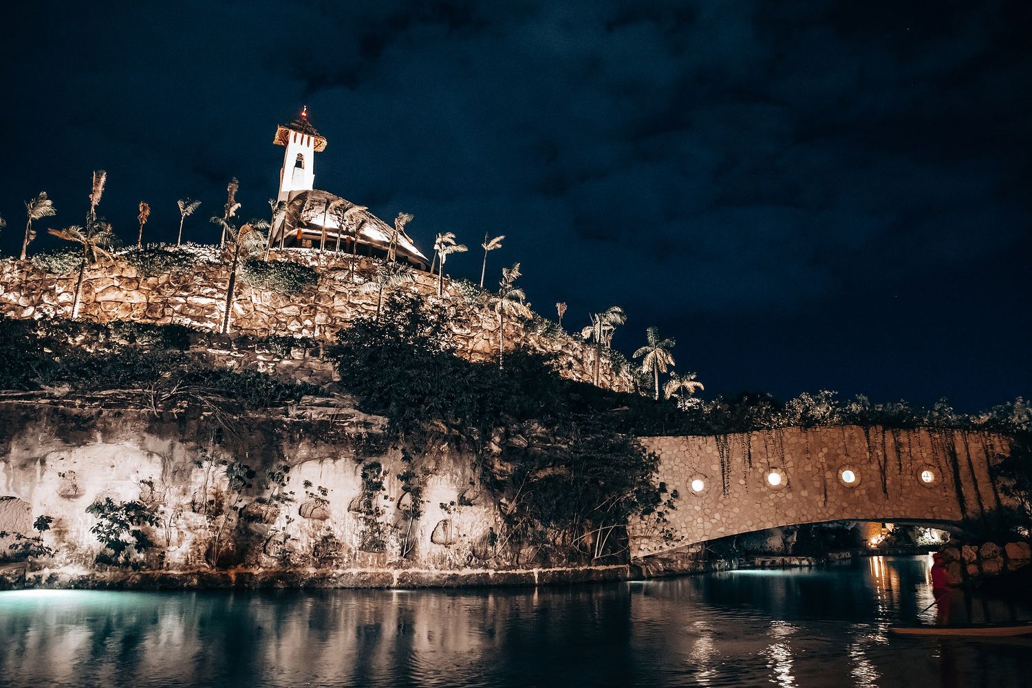 Panoramic view of a beach wedding venue illuminated at night with string lights.