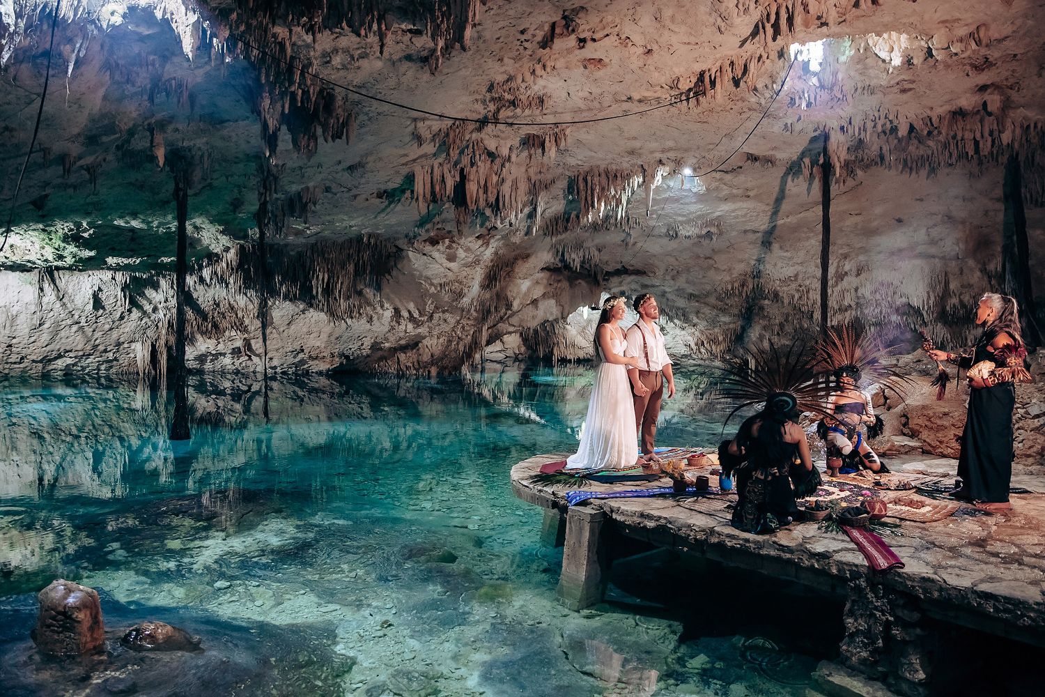 A mystical wedding ceremony takes place in a stunning cenote cave with turquoise waters and dramatic rock formations.