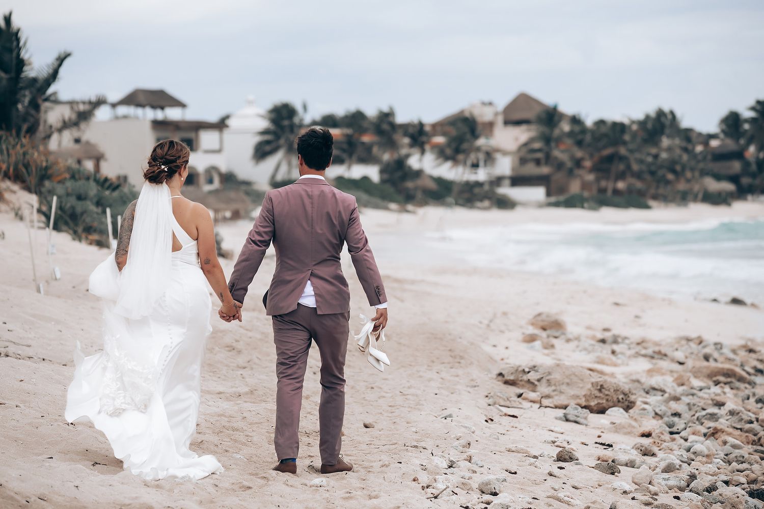 Beach wedding ceremony setup with guests walking along the shoreline.