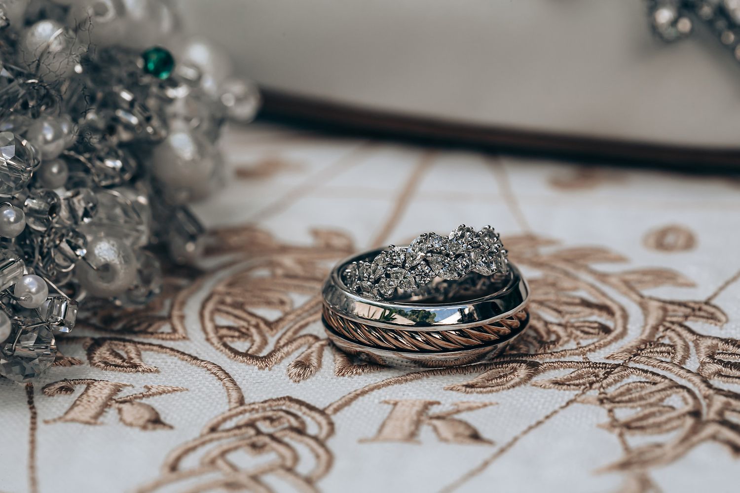 Close-up detail of ornate silver jewelry or decorative items arranged on a textured surface with intricate patterns.