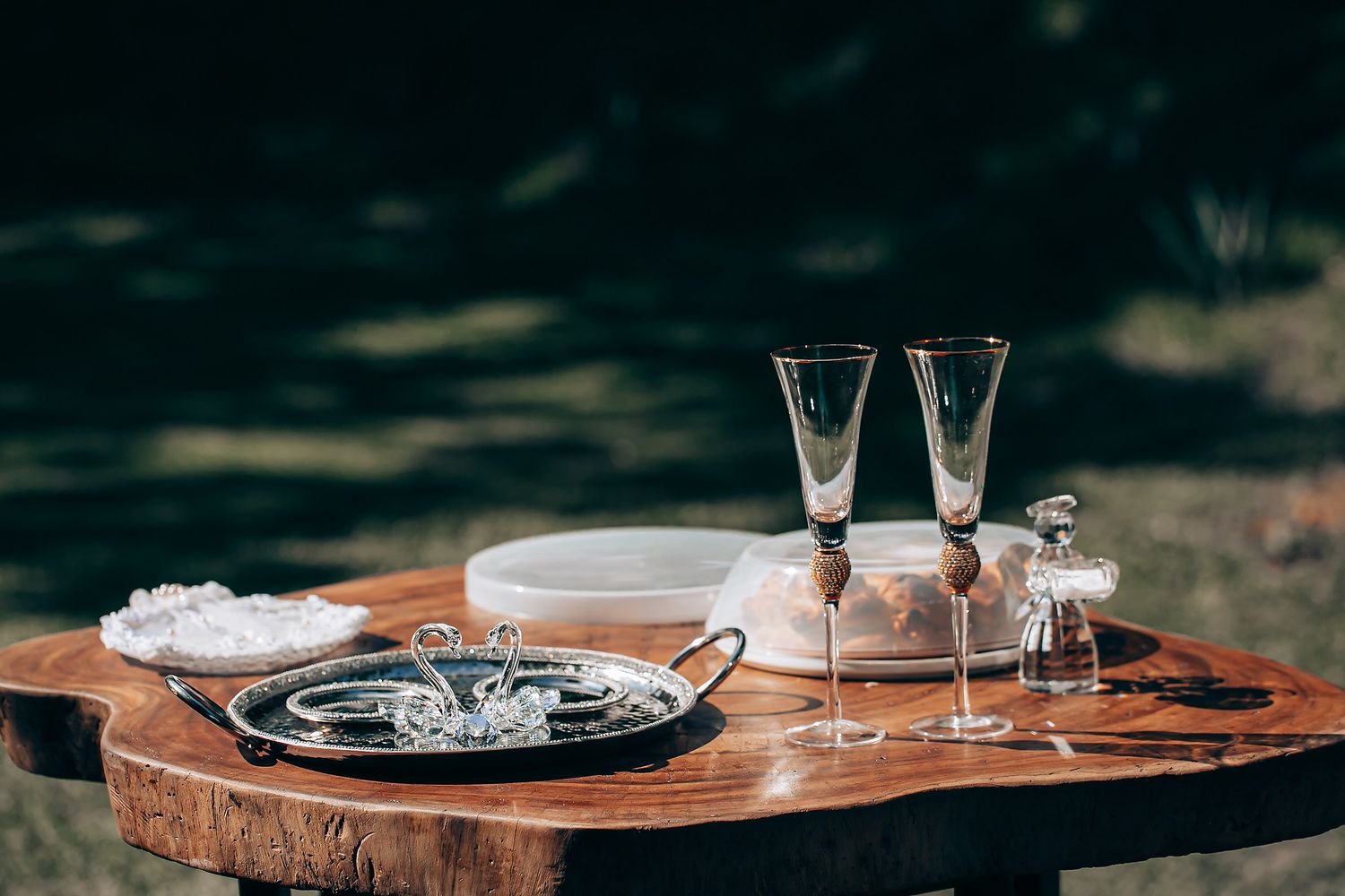 Crystal wine glasses sit on a rustic wooden table in a moody, dark setting with elegant lighting.