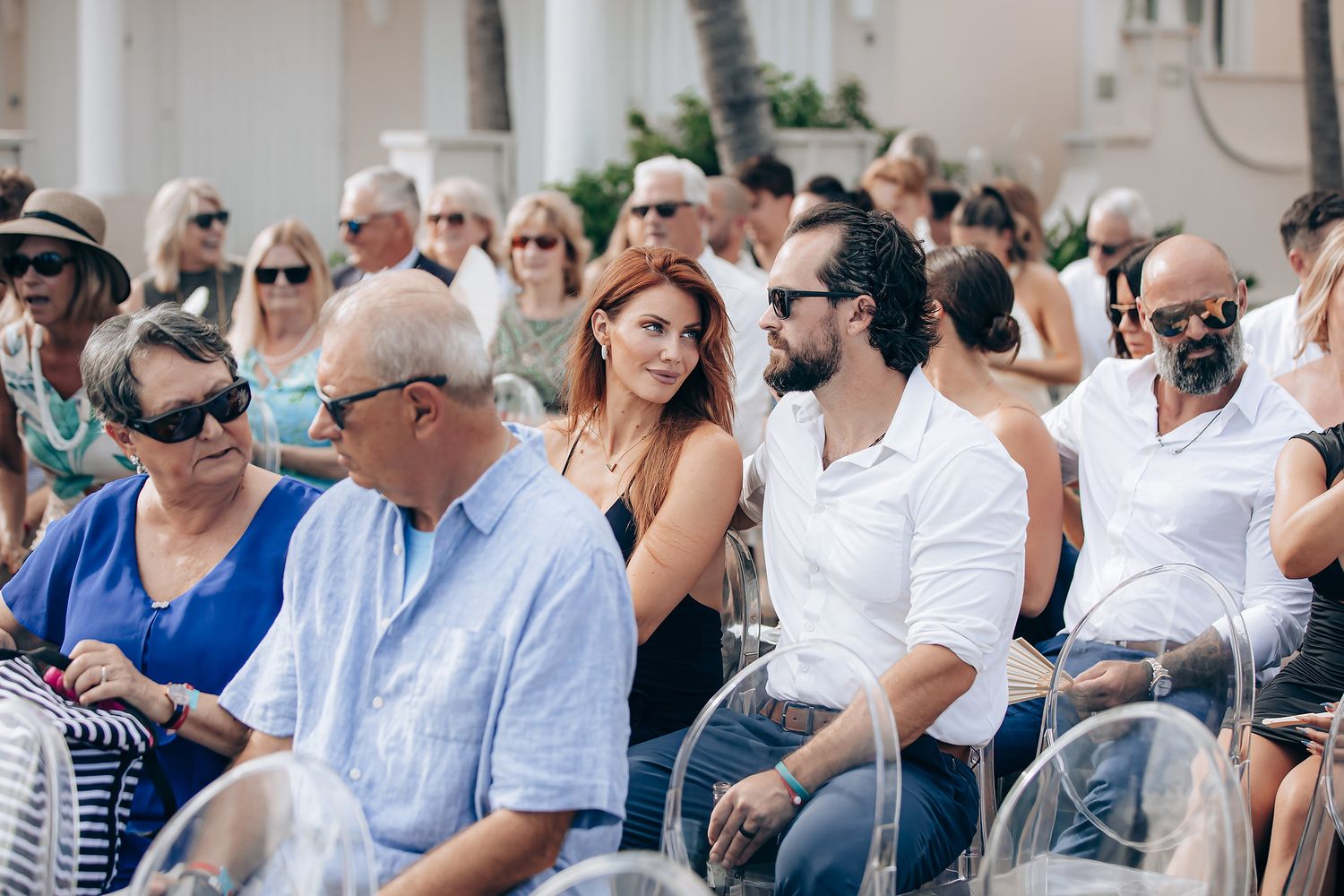 A large crowd of people gathered outdoors wearing casual summer attire in white and blue clothing.