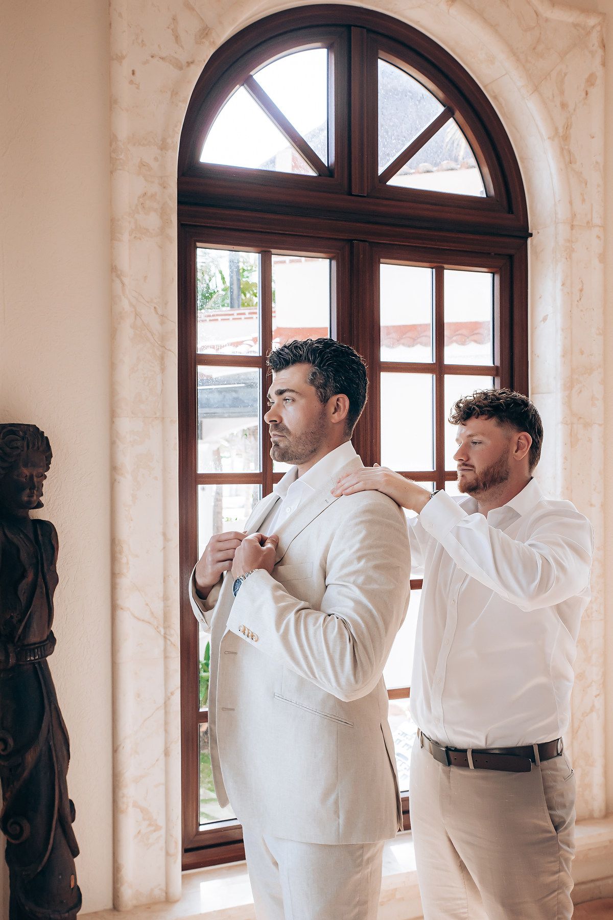 A sequence of four photos showing two people in white shirts adjusting their collars and ties by a window.