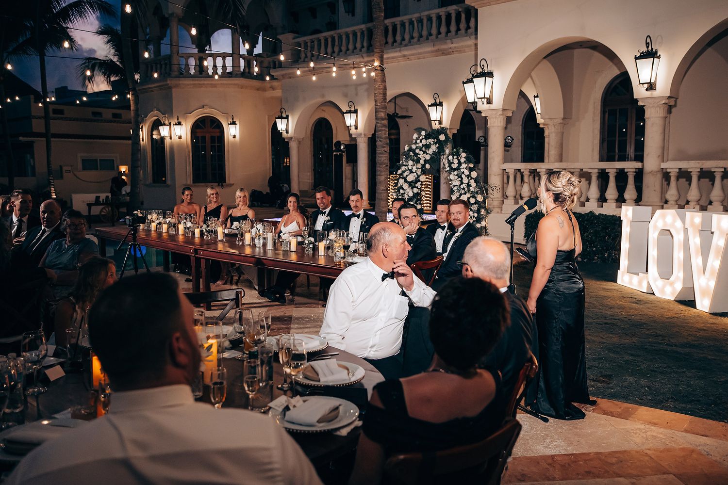 Wedding guests dance and celebrate on an illuminated dance floor during an evening reception.