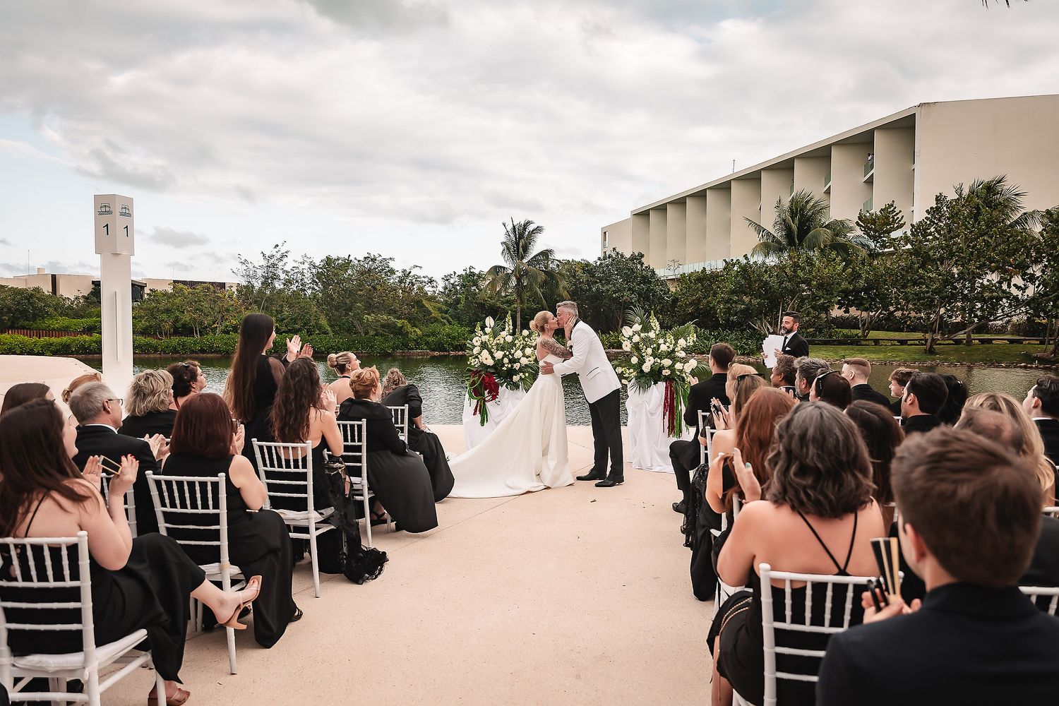 Wedding guests seated in white chairs during an outdoor ceremony overlooking a scenic ocean view.
