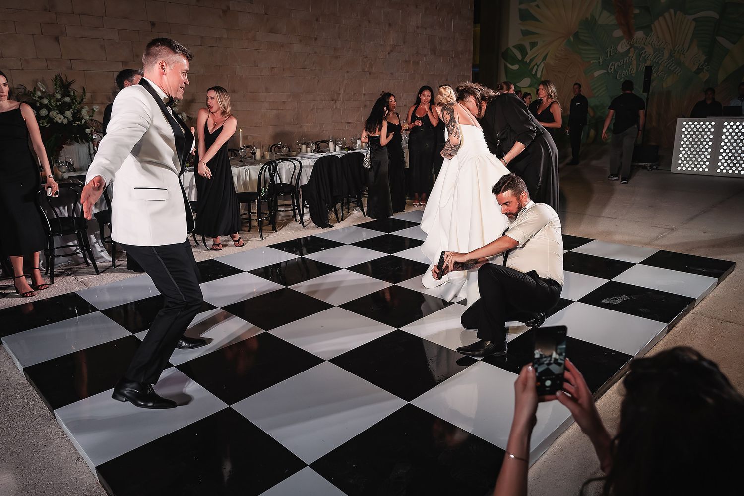 Wedding reception venue with black and white checkered dance floor and elegant table settings.
