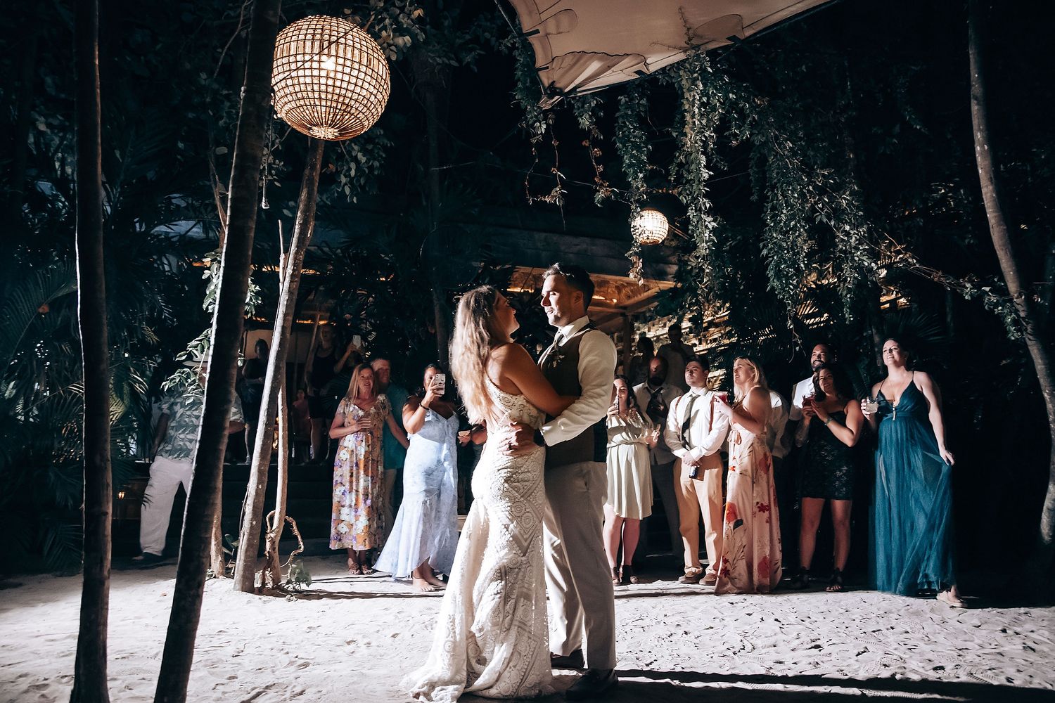 Wedding guests dance and celebrate under a sparkling disco ball at an outdoor evening reception.