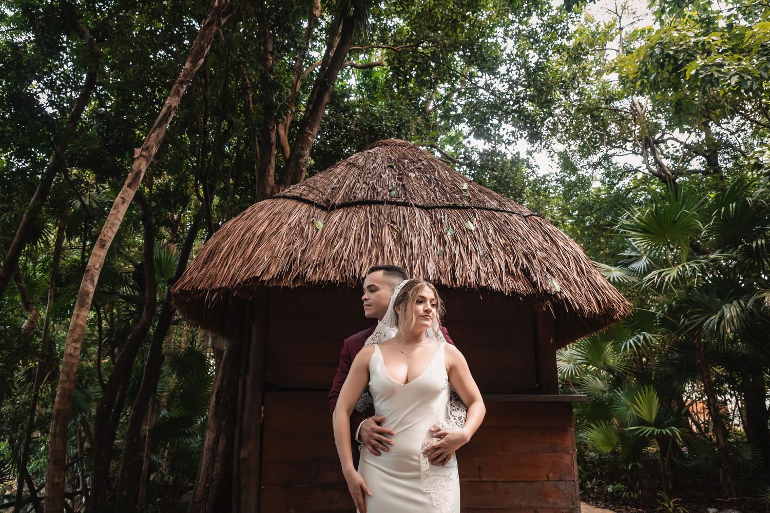Rustic thatched-roof huts nestled among tropical foliage create charming wedding venue setting.