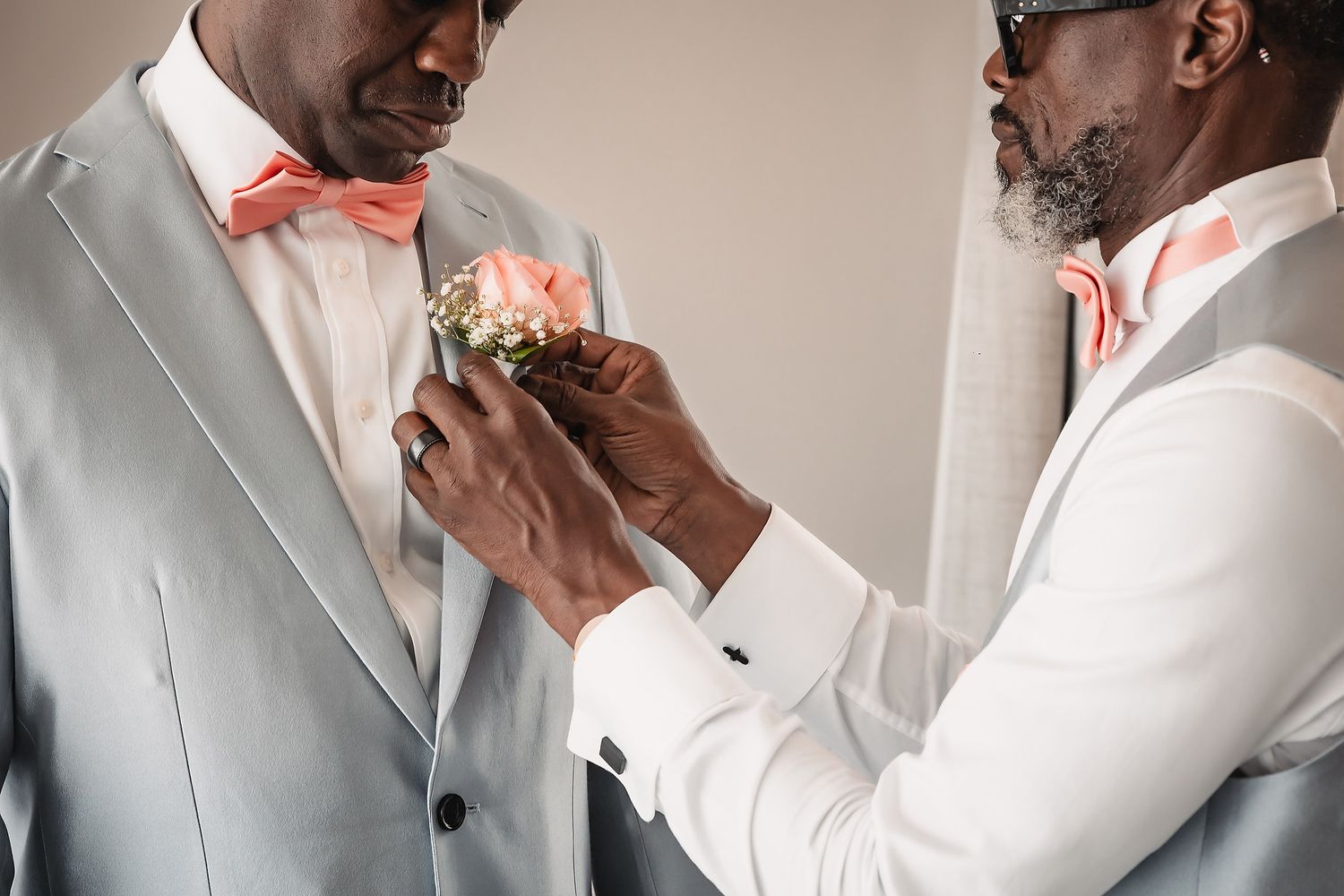 Wedding party members in light gray suits share emotional moments while getting ready.