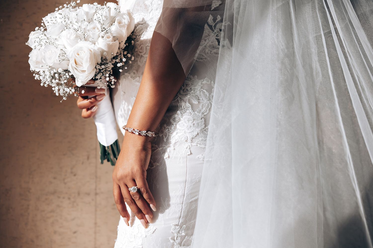 White wedding dress details with delicate lace and floral embellishments shown in close-up.