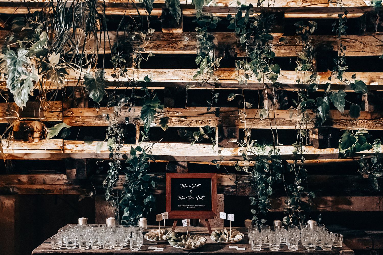 Wedding reception venue with rustic wooden beams and decorative greenery hanging from the ceiling.