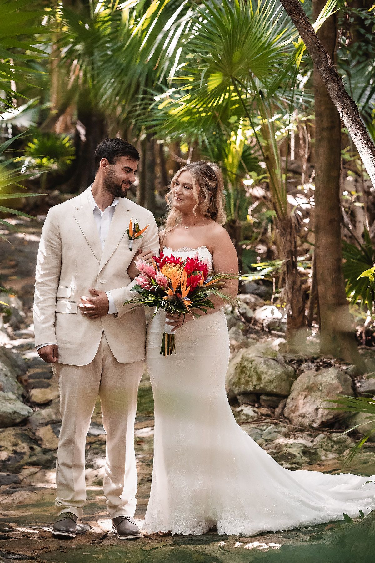 Tropical garden wedding photos with vibrant flowers and palm trees in the background.