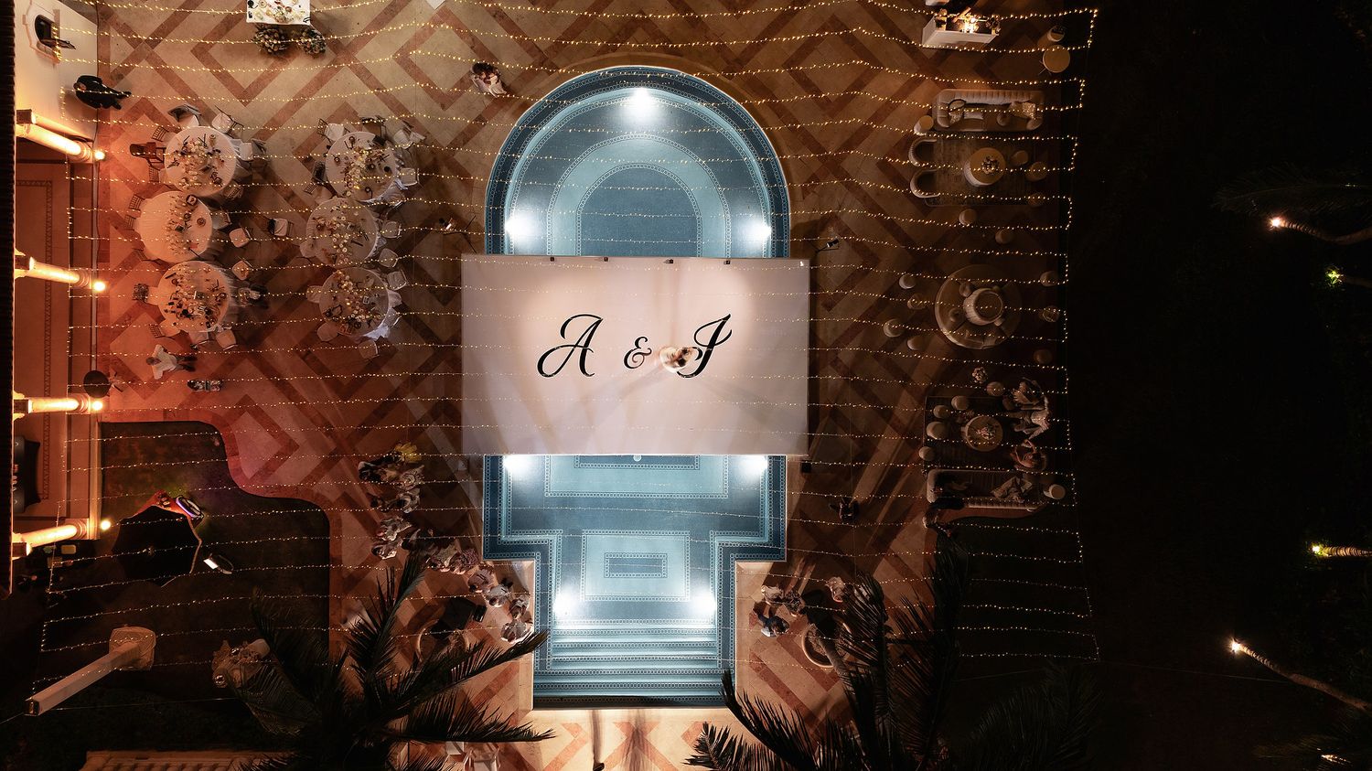 Illuminated architectural detail showing monogram projection on arched window at night.