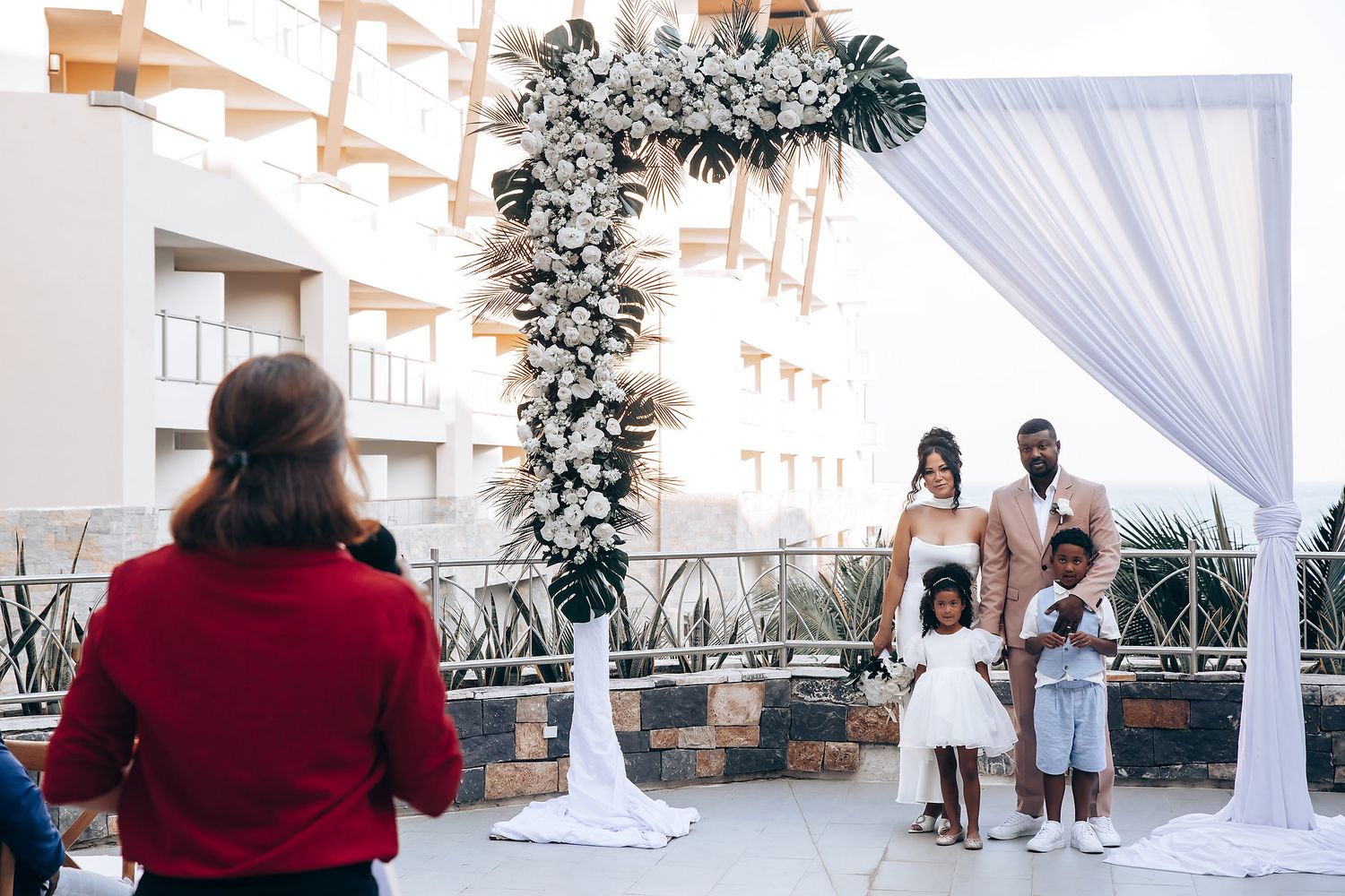 Wedding ceremony setup with white drapes and decorations under covered outdoor venue.