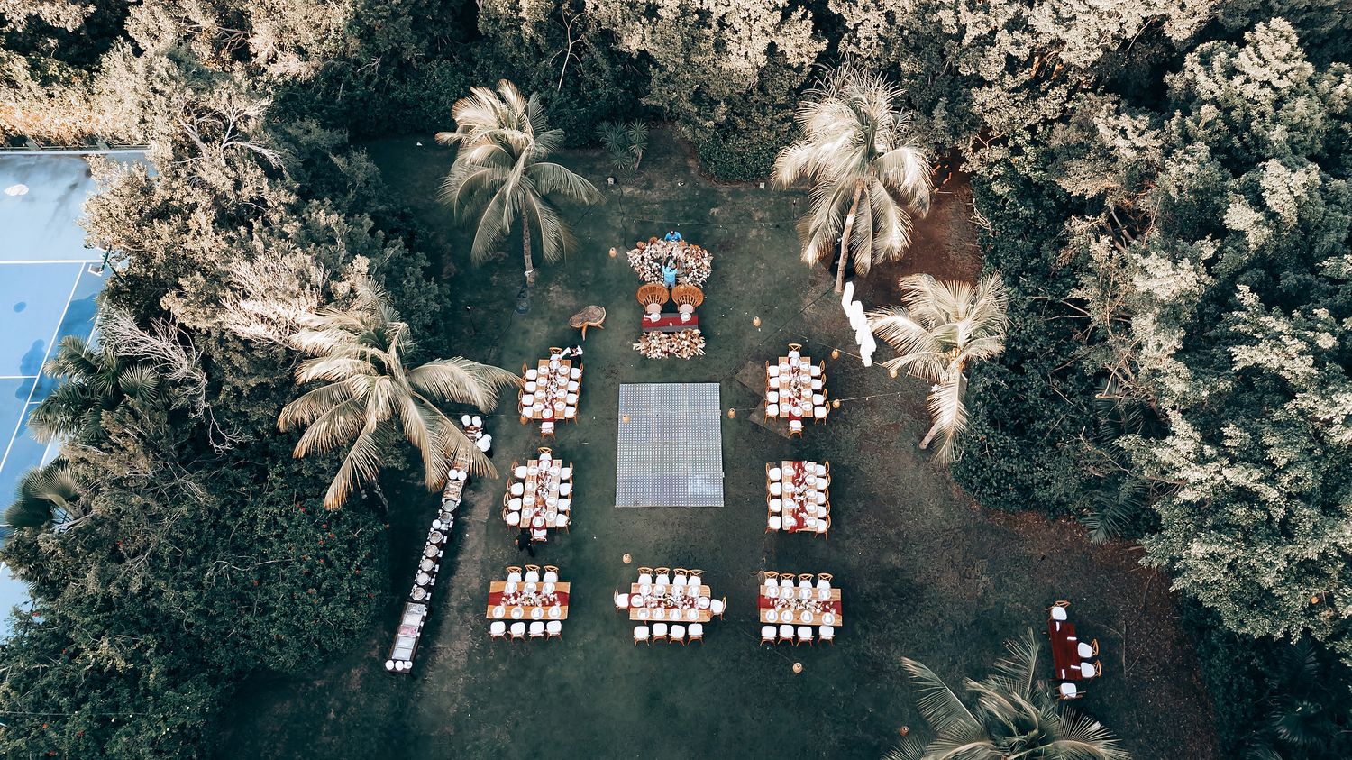 Aerial view of an outdoor wedding venue surrounded by palm trees and tropical landscaping.