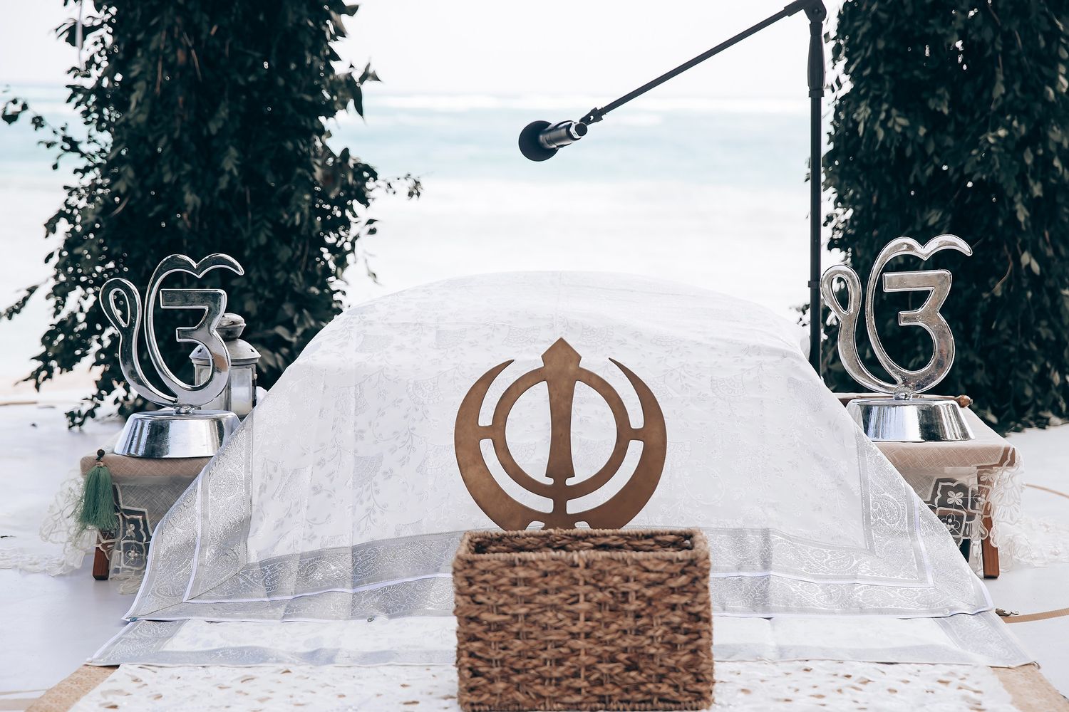 White floral archway with decorative Sikh Khanda symbol for a traditional wedding ceremony.
