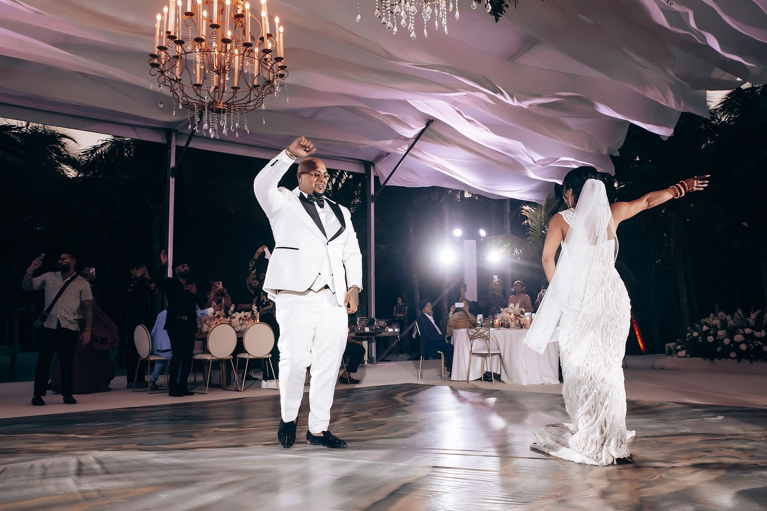 Dynamic dance moment captured under elegant chandeliers at evening reception.