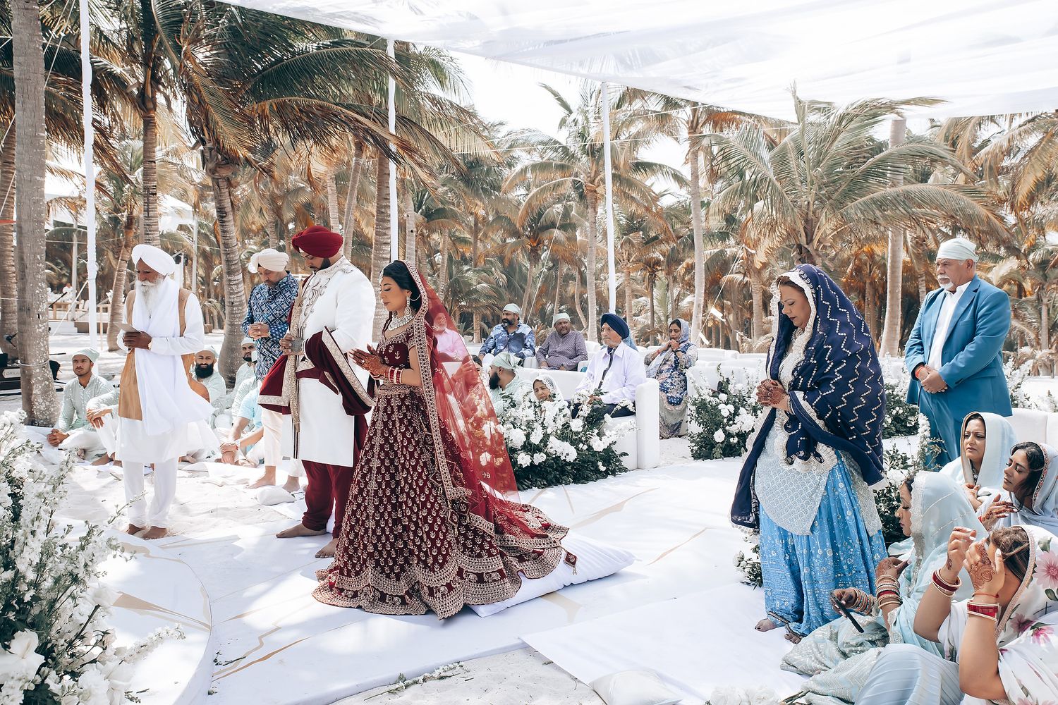 Panoramic view of a beach wedding setup with palm trees and white chairs.