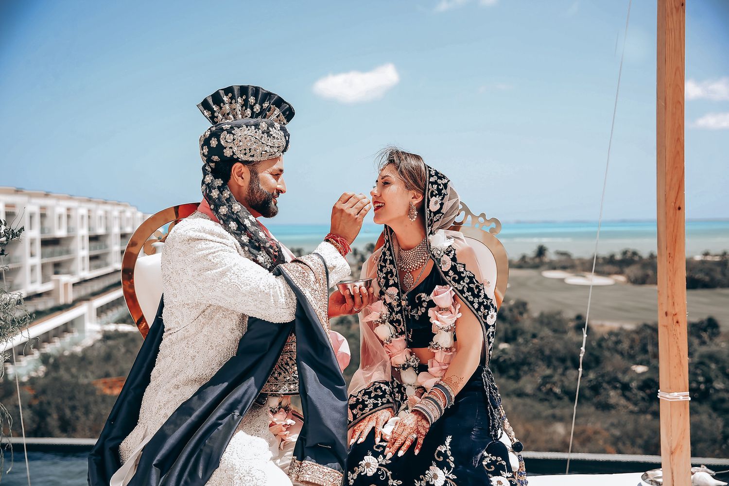 A romantic outdoor wedding ceremony with ocean views and wooden arch decorations.