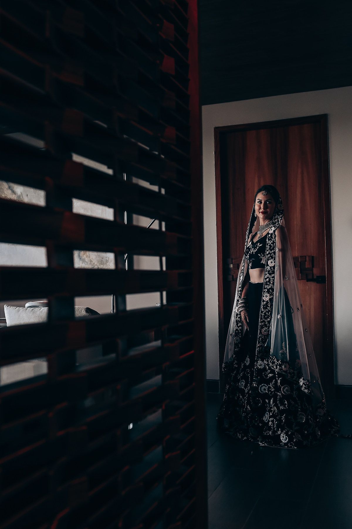 Dramatic dark portrait of traditional South Asian bridal attire with intricate embellishments.