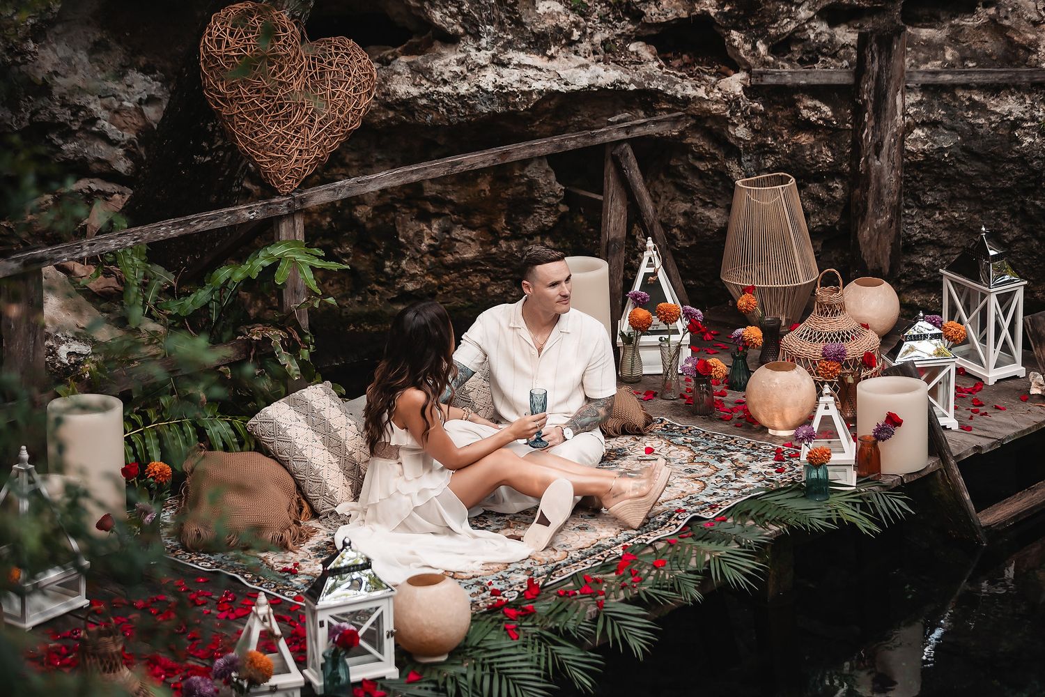 Intimate outdoor setting with decorative lanterns and floral arrangements on stone ledge.