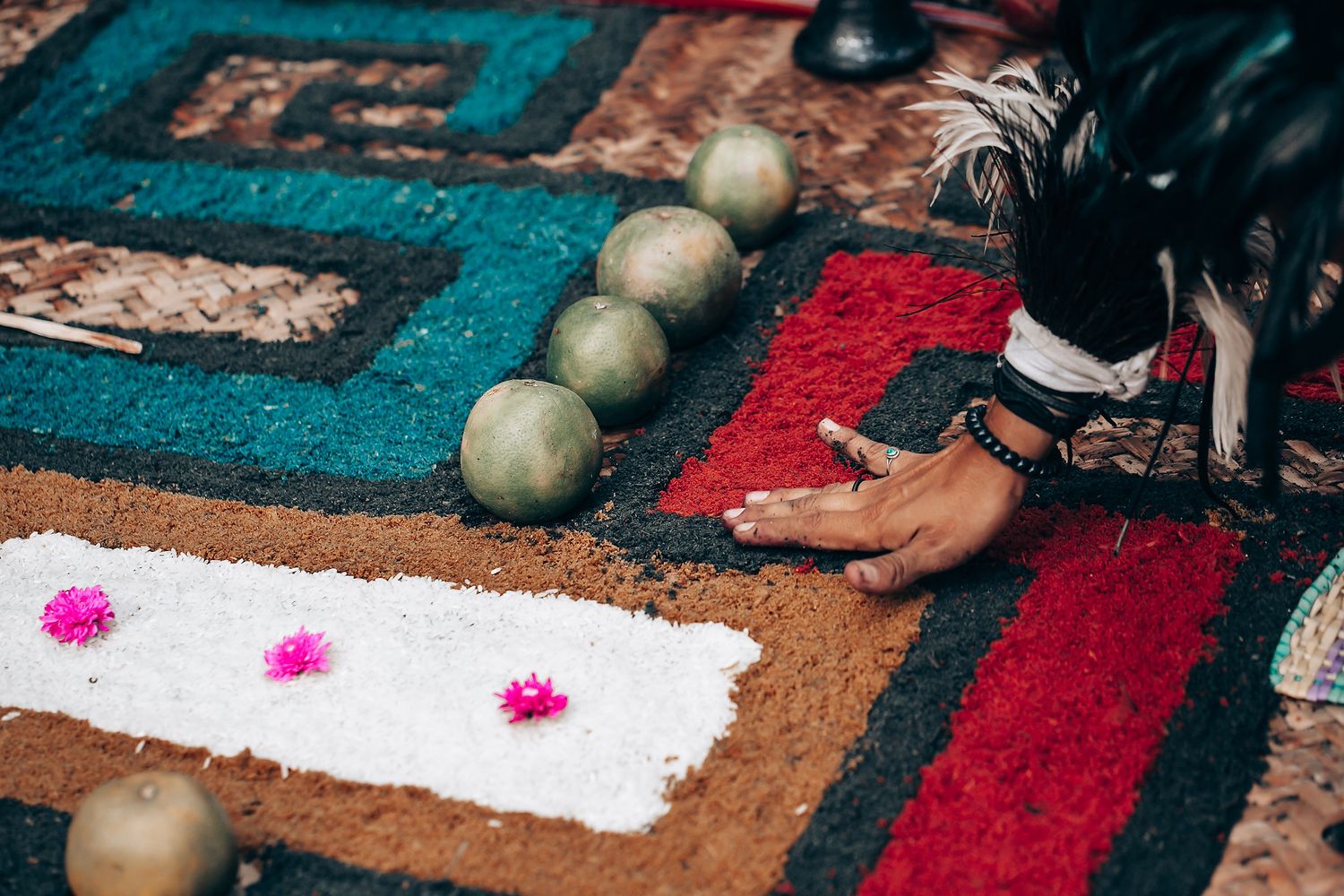 Guests toss red flower petals during an outdoor wedding celebration in a natural setting.