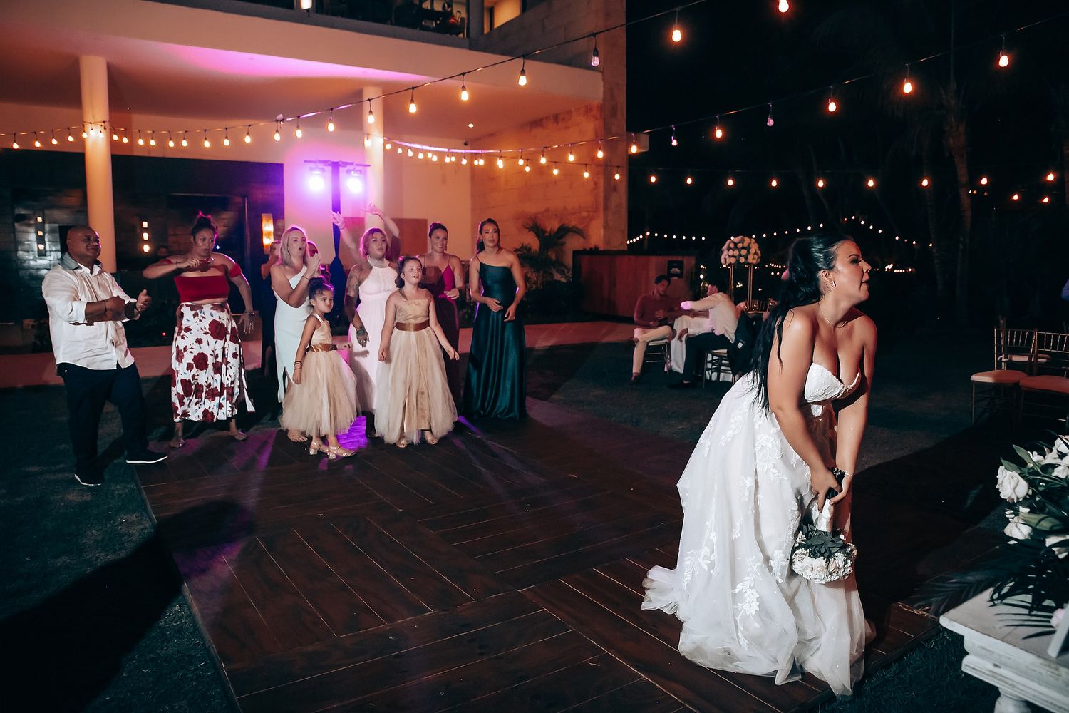 Wedding reception dance floor scene with guests and string lights creating a romantic atmosphere.