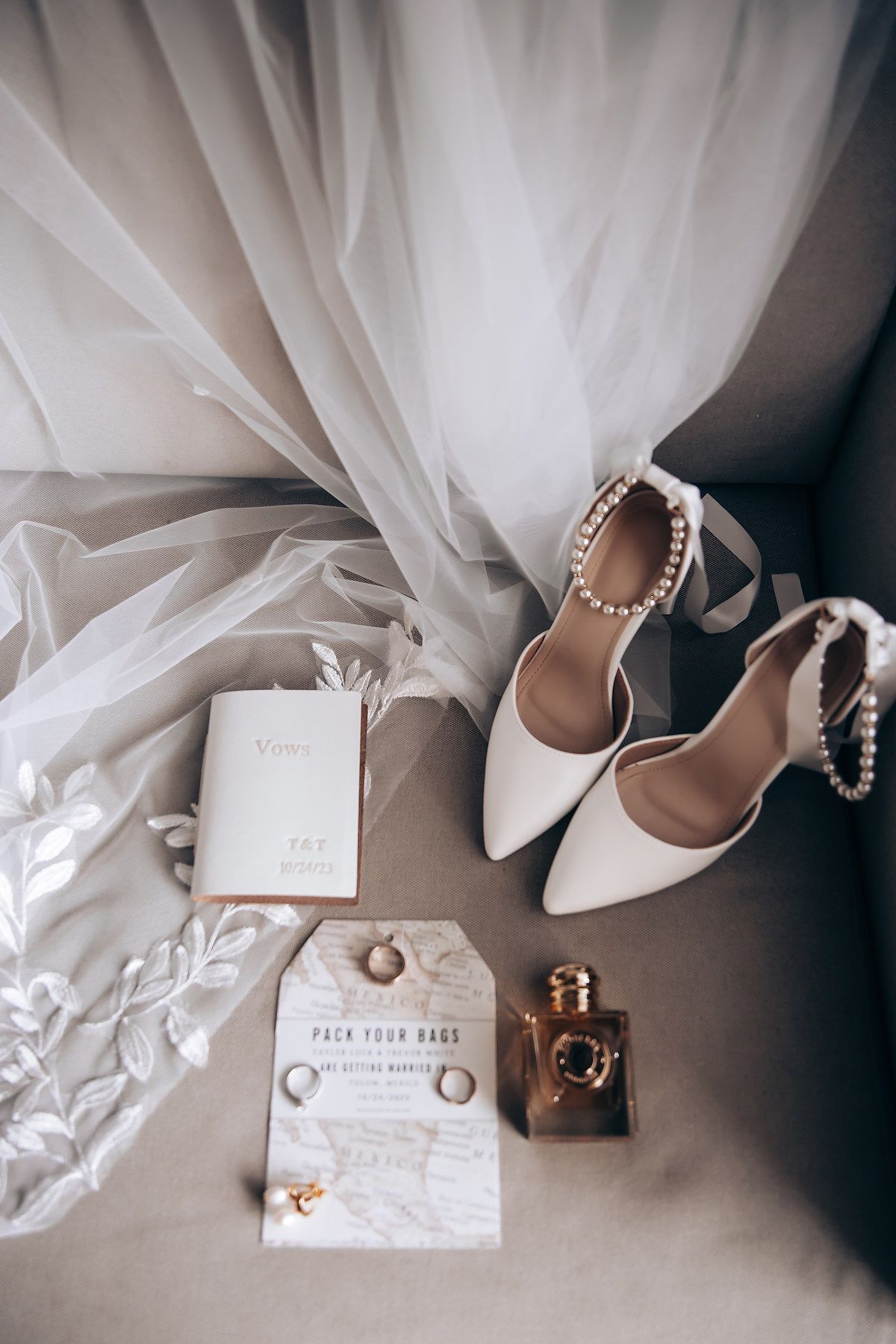 White wedding shoes, veil, and invitation details arranged artistically on a neutral gray surface in a minimalist style.