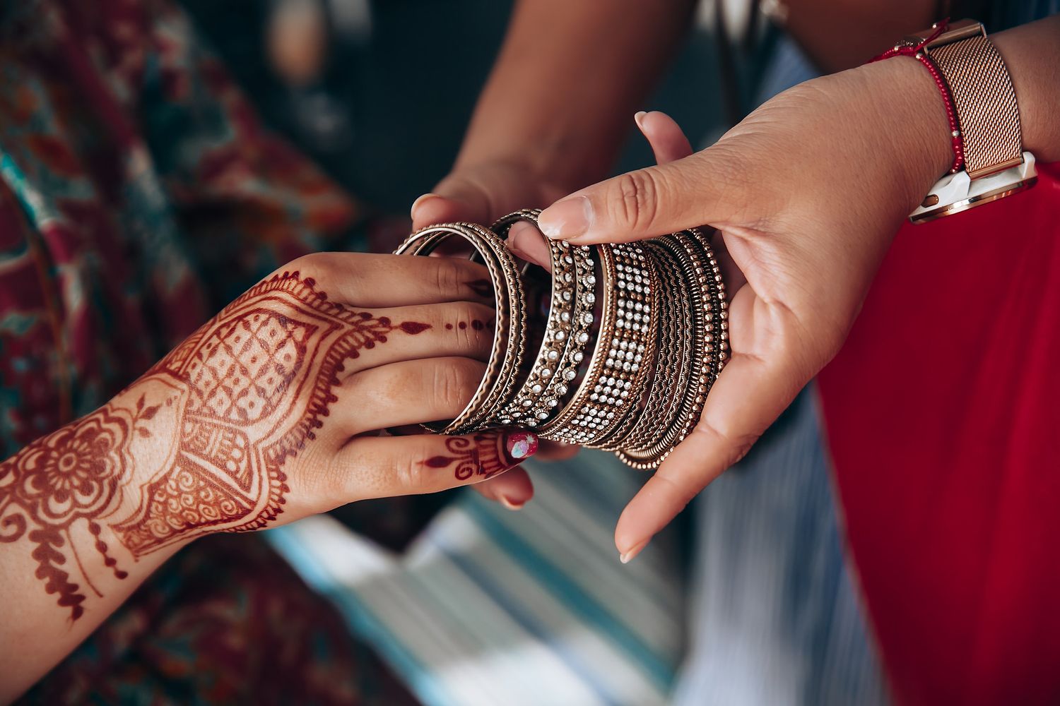 Close-up shots of hands adorned with intricate henna designs and traditional Indian bangles.