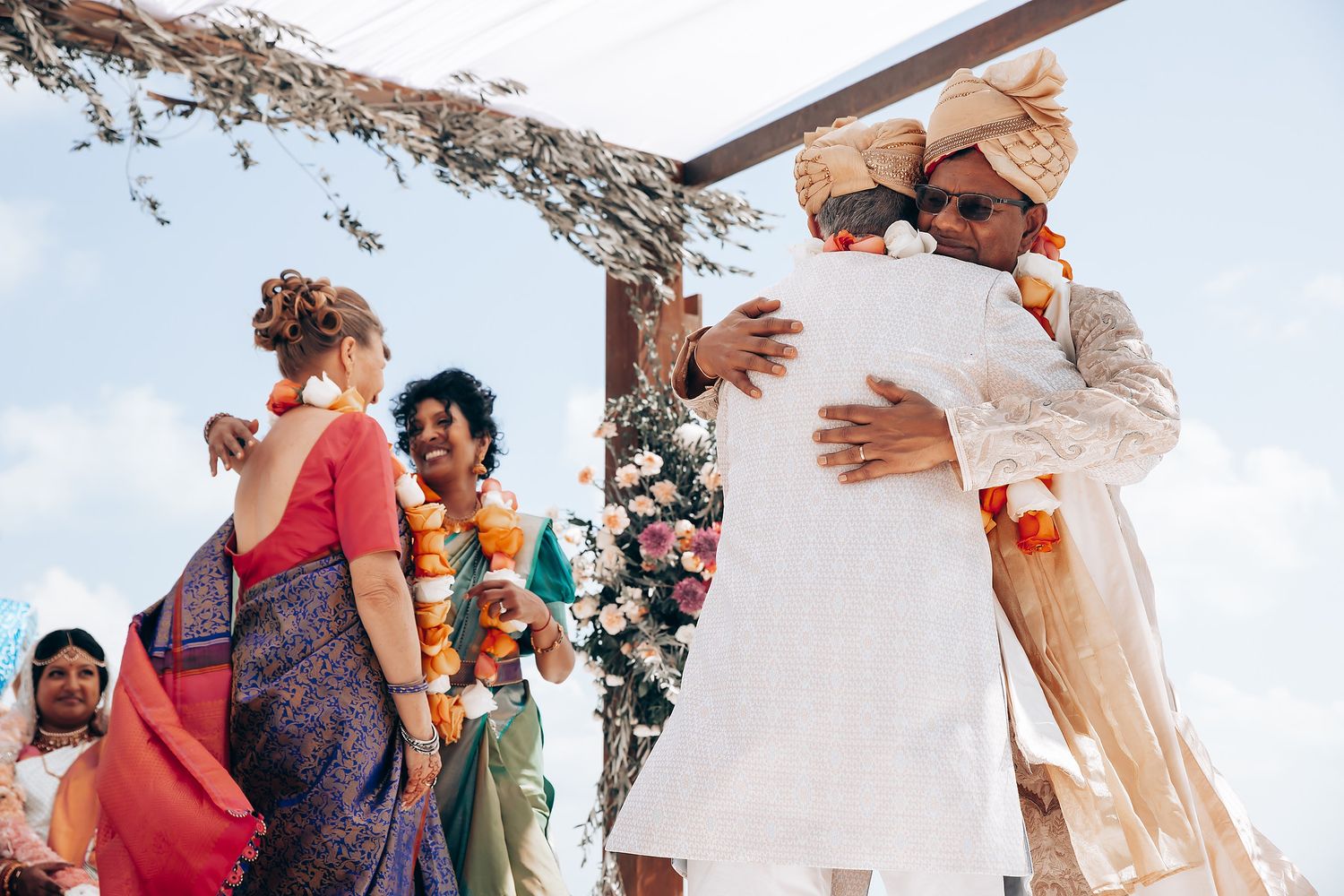 Guests celebrate during an outdoor wedding reception with tropical decor.
