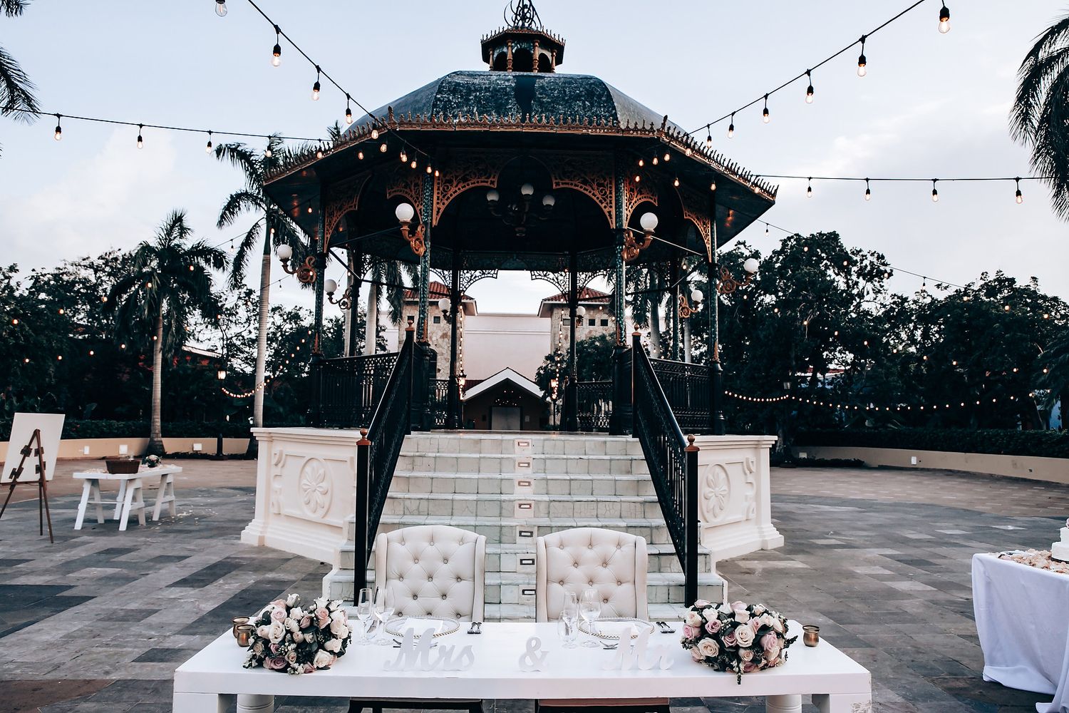 Outdoor wedding venue with string lights and gazebo decorated for an evening celebration.