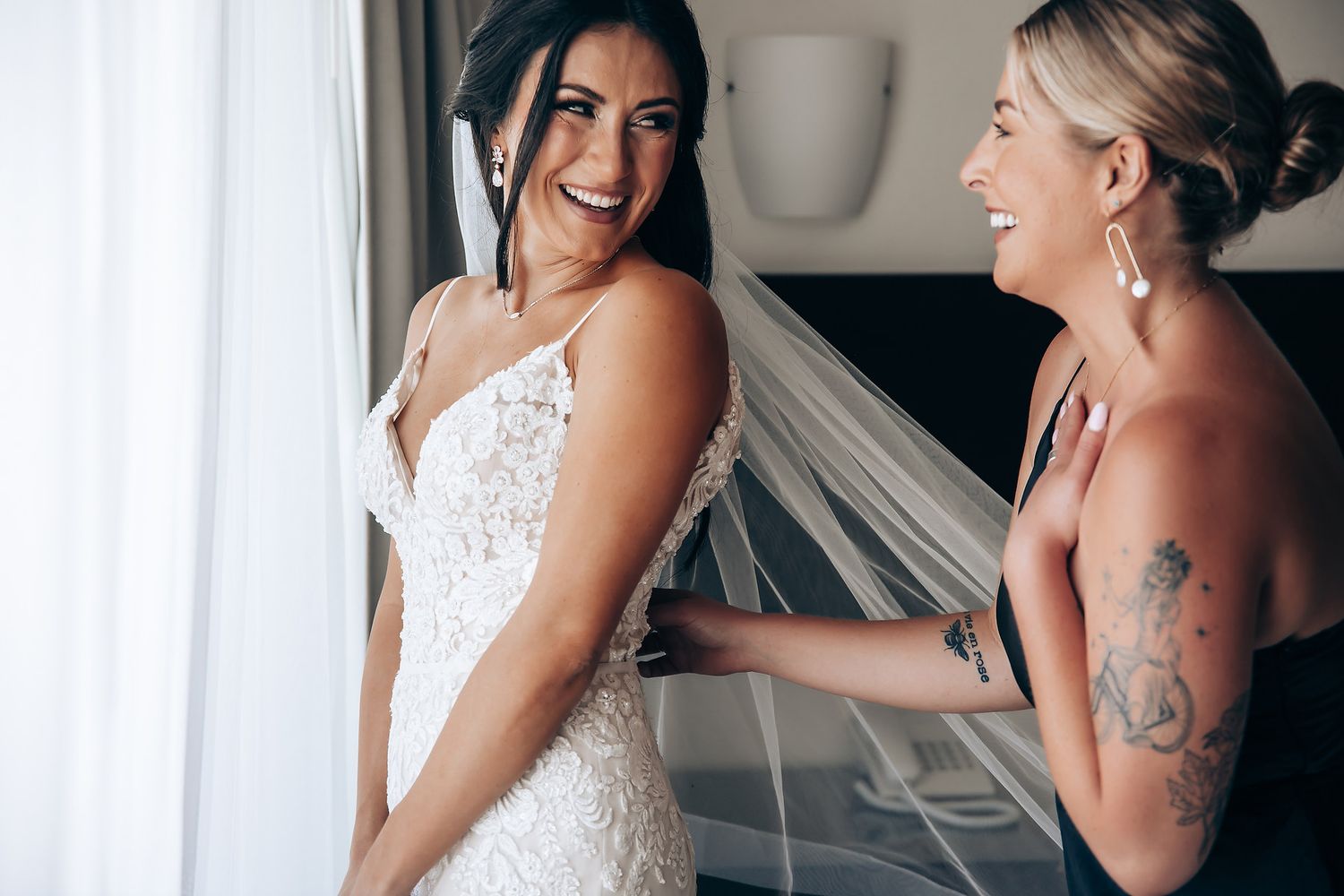 Wedding preparation scene with people in white dresses sharing a joyful moment.